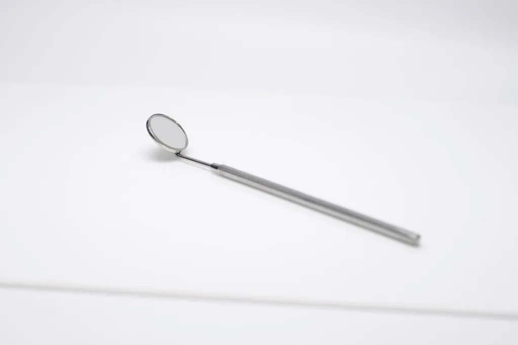 A dental mirror resting on a white surface
