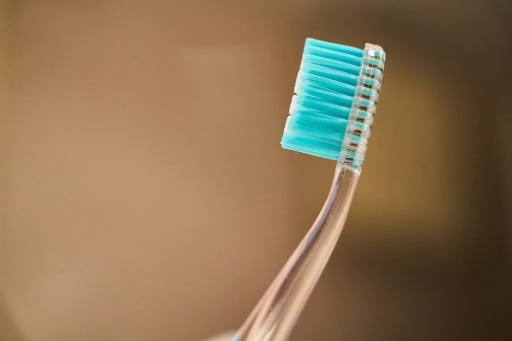 A toothbrush with teal bristles against a plain background